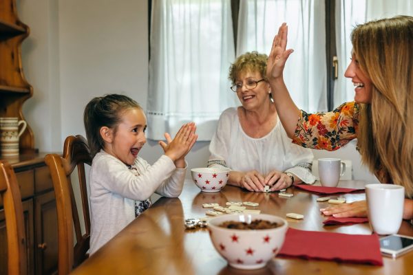 Little girl winning domino her mother and her grandmother